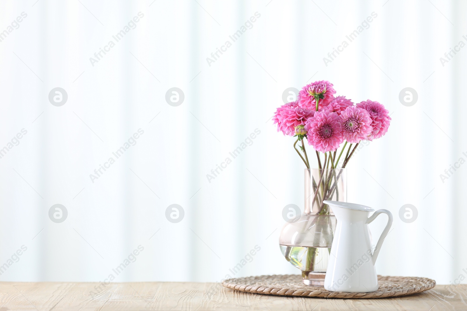 Photo of Beautiful pink flowers in vase on wooden table at home. Space for text