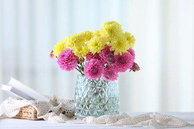 Photo of Beautiful yellow and pink flowers in vase on white wooden table at home