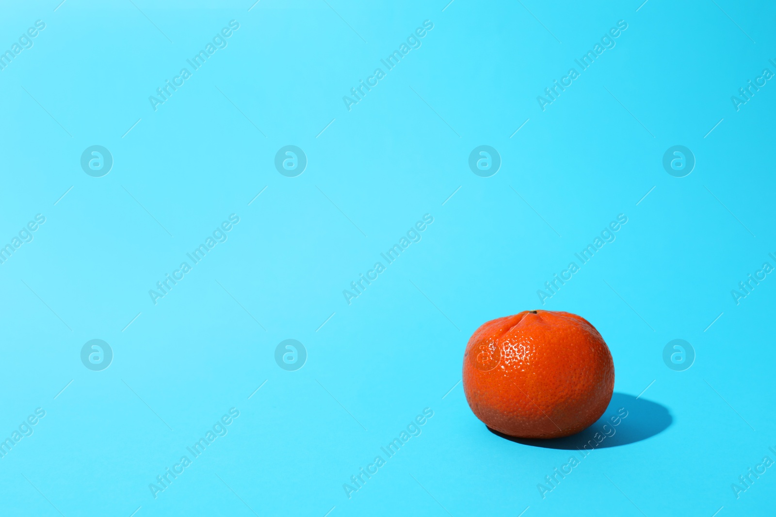 Photo of Fresh ripe tangerine on light blue background. Space for text