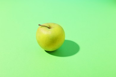 Photo of Fresh ripe apple on light green background