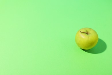 Photo of Fresh ripe apple on light green background, space for text