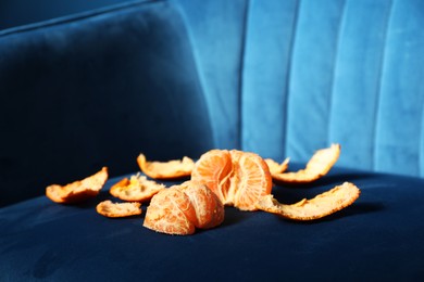 Photo of Fresh peeled tangerine on dark blue armchair