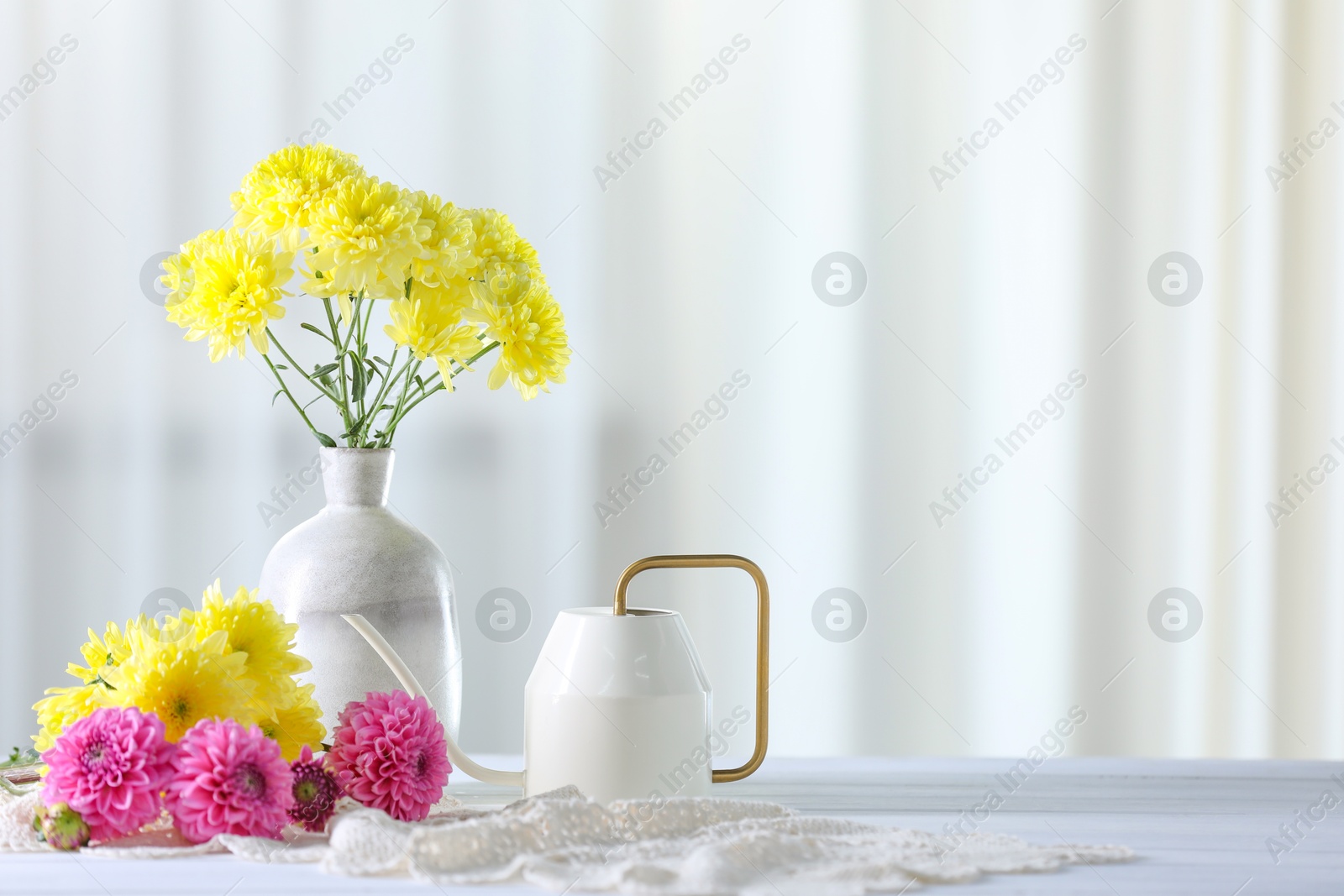 Photo of Beautiful flowers in vase on white wooden table at home. Space for text