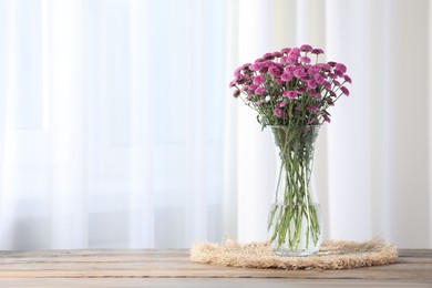 Photo of Beautiful pink flowers in vase on wooden table indoors. Space for text