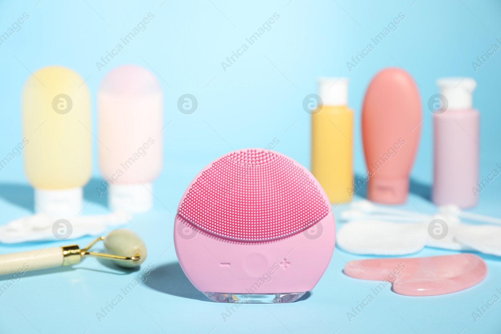 Photo of Facial cleansing brush and other skin care products on light blue background