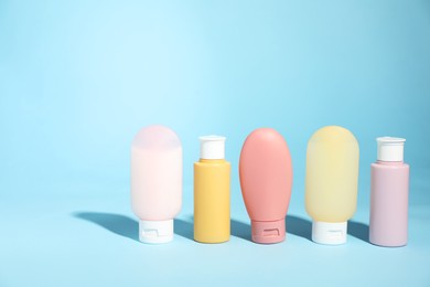 Photo of Bottles of different skin care products on light blue background