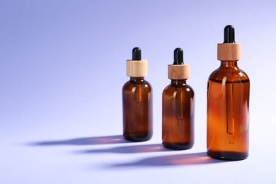 Photo of Bottles of skin care products on violet background, space for text