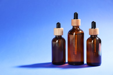 Photo of Bottles of skin care products on blue background, space for text