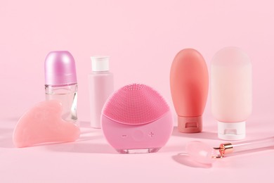 Photo of Facial cleansing brush and other body care products on pink background