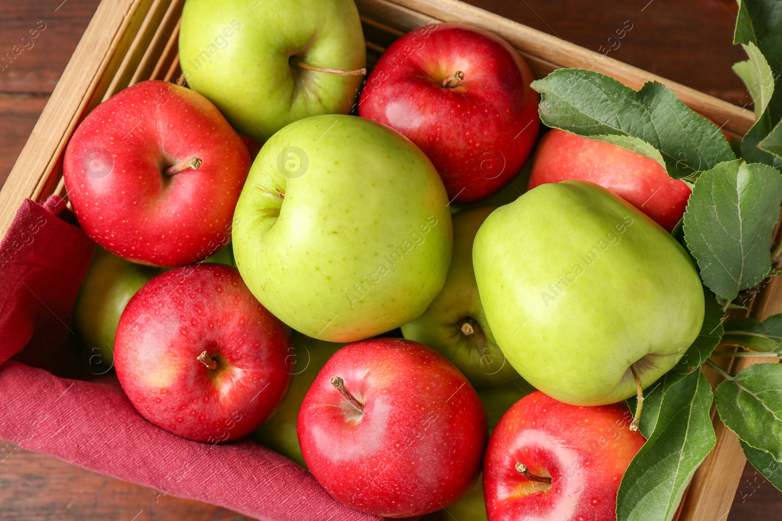 Photo of Ripe red and green apples in wooden crate on table, top view