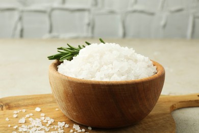 Photo of Sea salt and rosemary in bowl on grey table, closeup