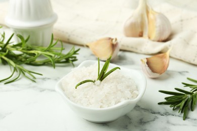 Photo of Sea salt, rosemary and garlic on white marble table, closeup