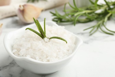 Photo of Sea salt, rosemary and garlic on white marble table, closeup