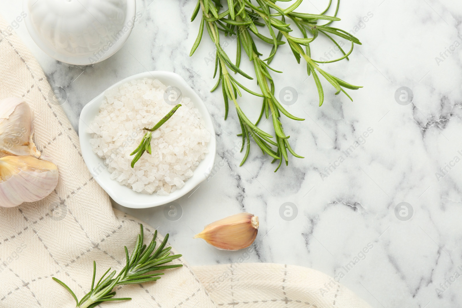 Photo of Sea salt, rosemary and garlic on white marble table, top view. Space for text