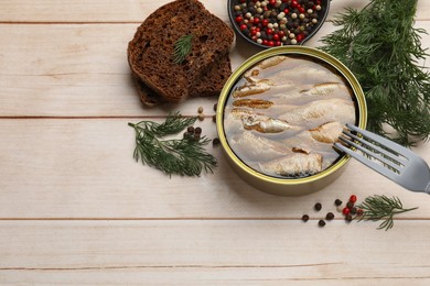 Photo of Tasty sprats in tin can, dill, bread and peppercorns on wooden table, above view. Space for text