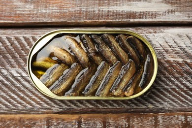 Photo of Tasty sprats in tin can on wooden table, top view