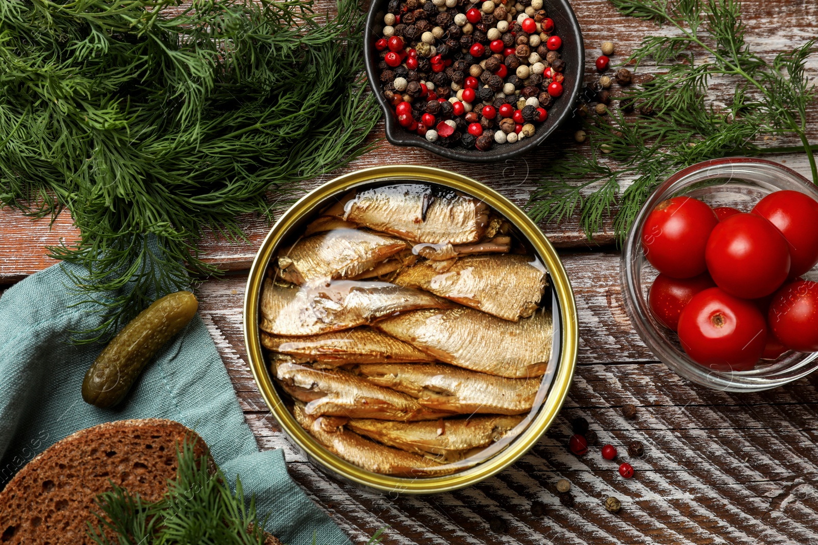 Photo of Tasty sprats in tin can served on wooden table, flat lay