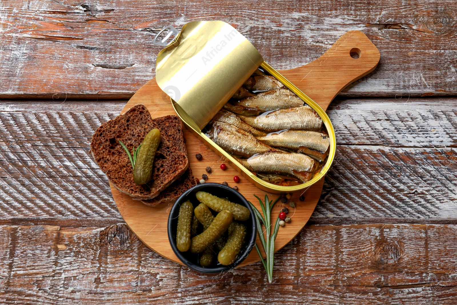 Photo of Tasty sprats in tin can served on wooden table, top view