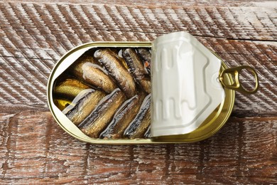 Photo of Tasty sprats in tin can on wooden table, top view