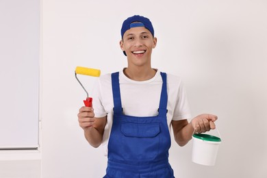 Smiling handyman with roller and paint indoors