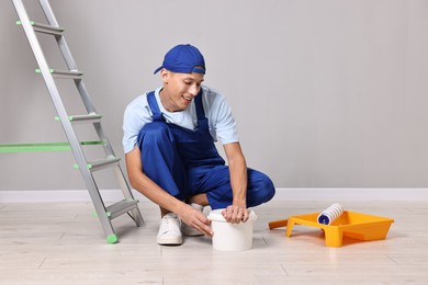 Photo of Smiling handyman preparing to painting wall indoors