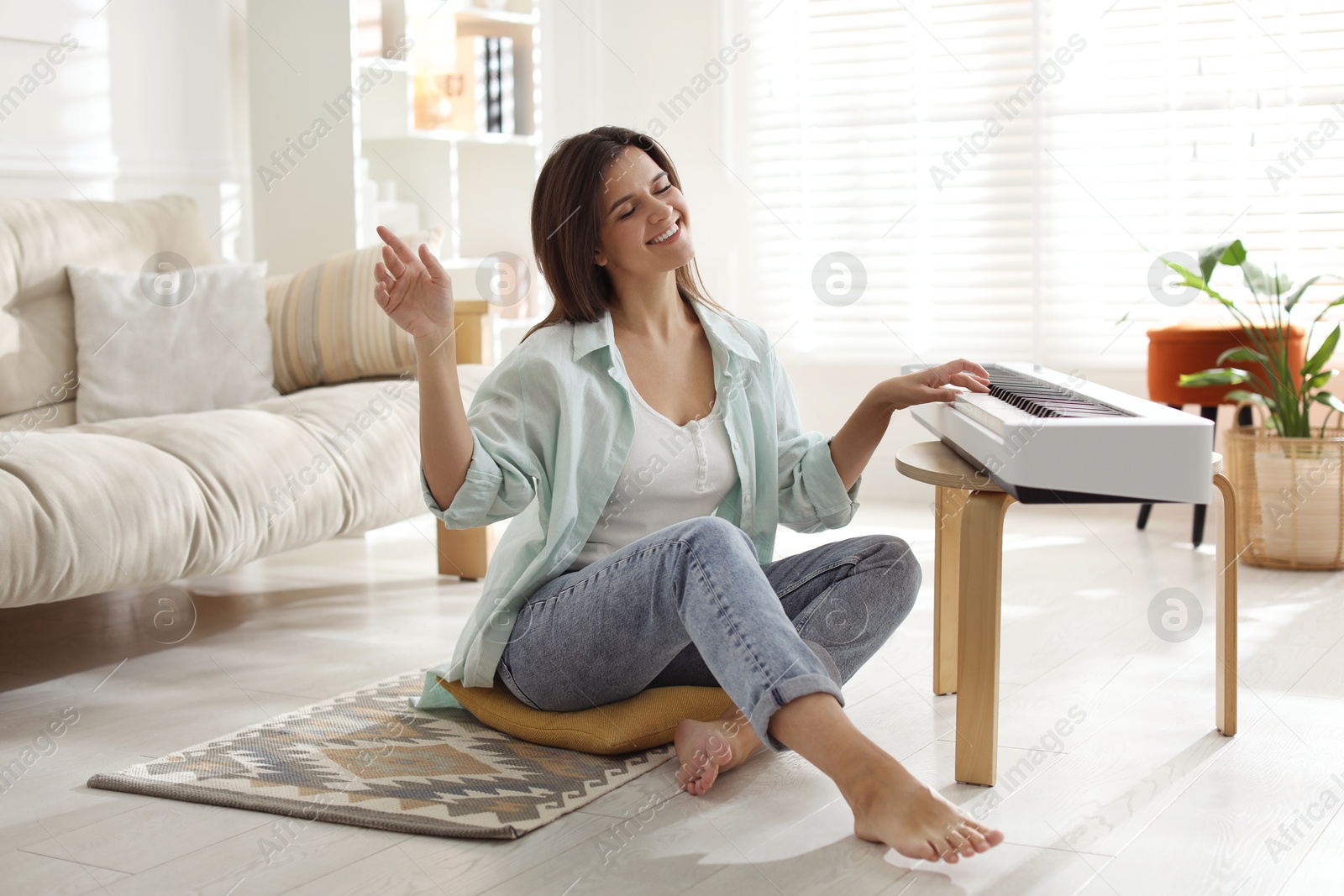 Photo of Smiling woman playing synthesizer on floor at home