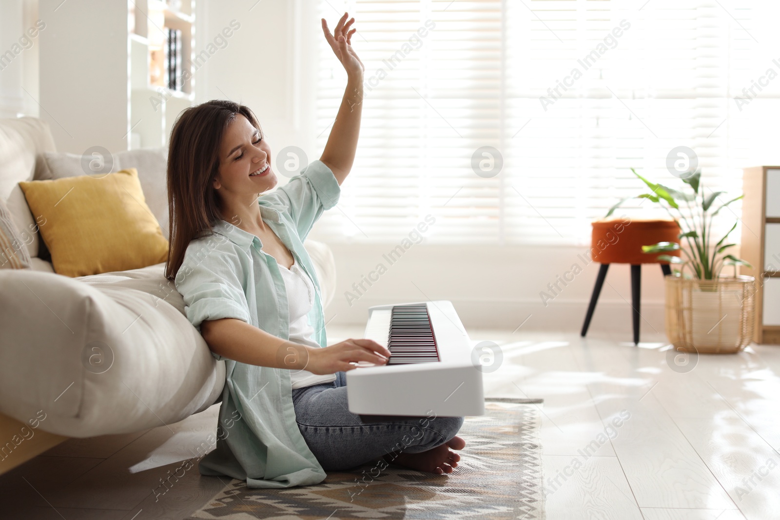 Photo of Smiling woman playing synthesizer on floor at home. Space for text