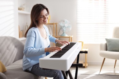 Photo of Smiling woman playing synthesizer at home, space for text