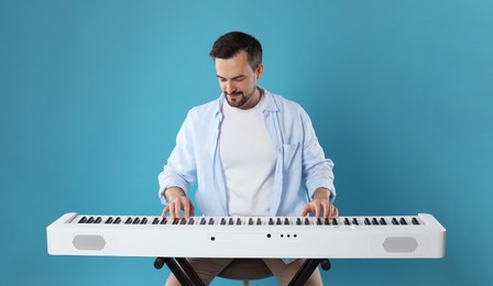 Photo of Man playing synthesizer on light blue background