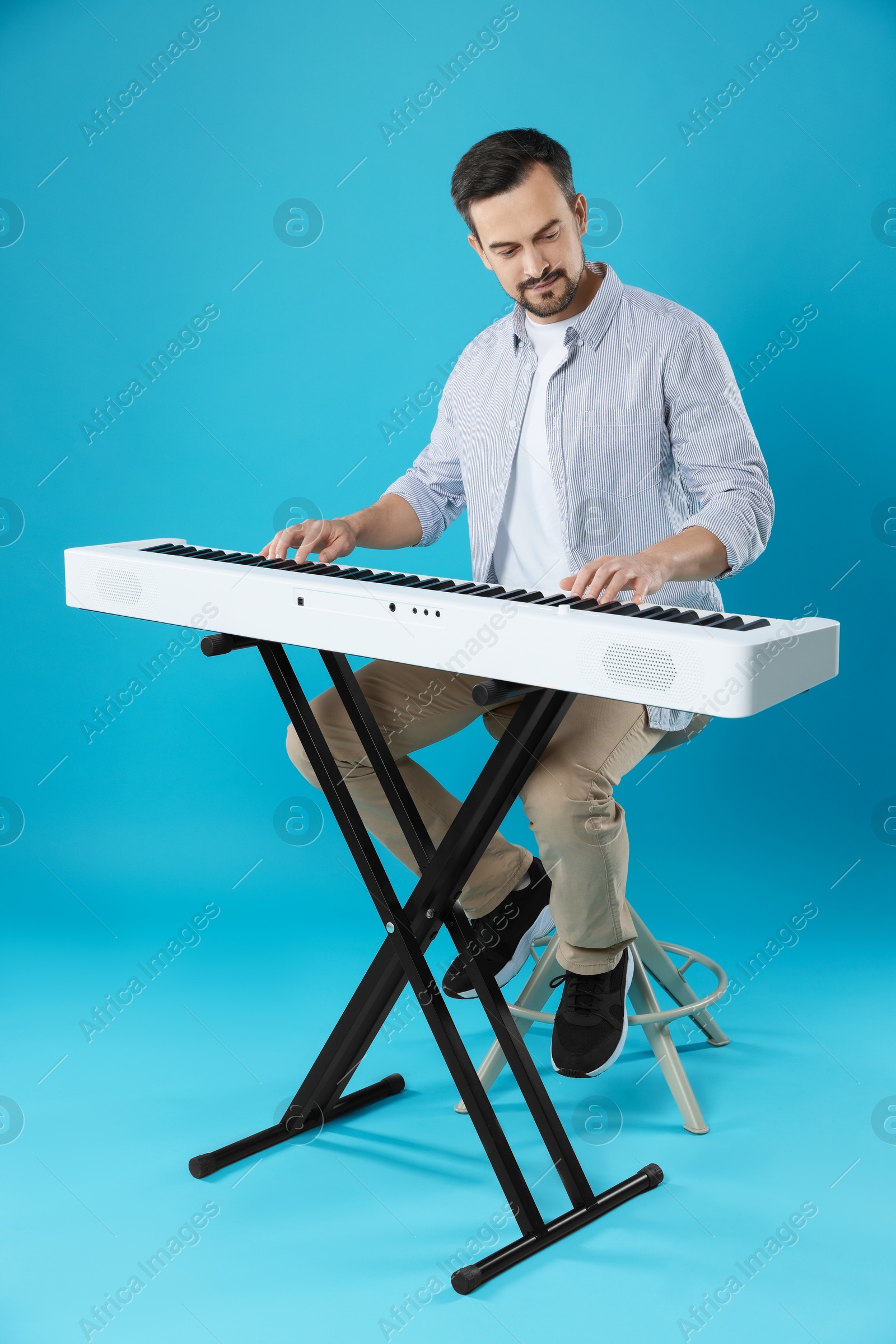 Photo of Man playing synthesizer on light blue background