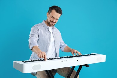 Photo of Smiling man playing synthesizer on light blue background