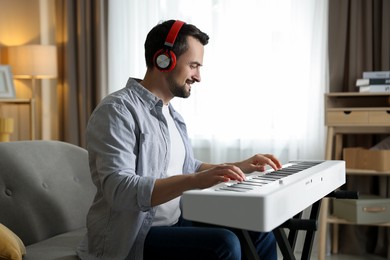 Photo of Smiling man in headphones playing synthesizer at home