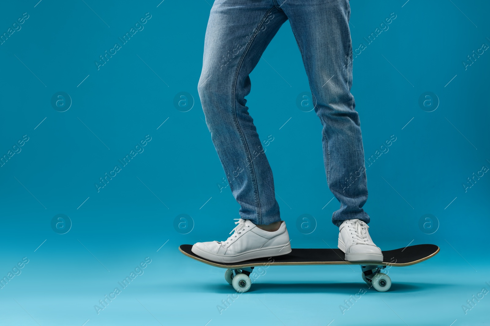 Photo of Man riding skateboard on light blue background, closeup. Space for text