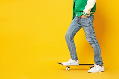 Photo of Man with skateboard on orange background, closeup. Space for text