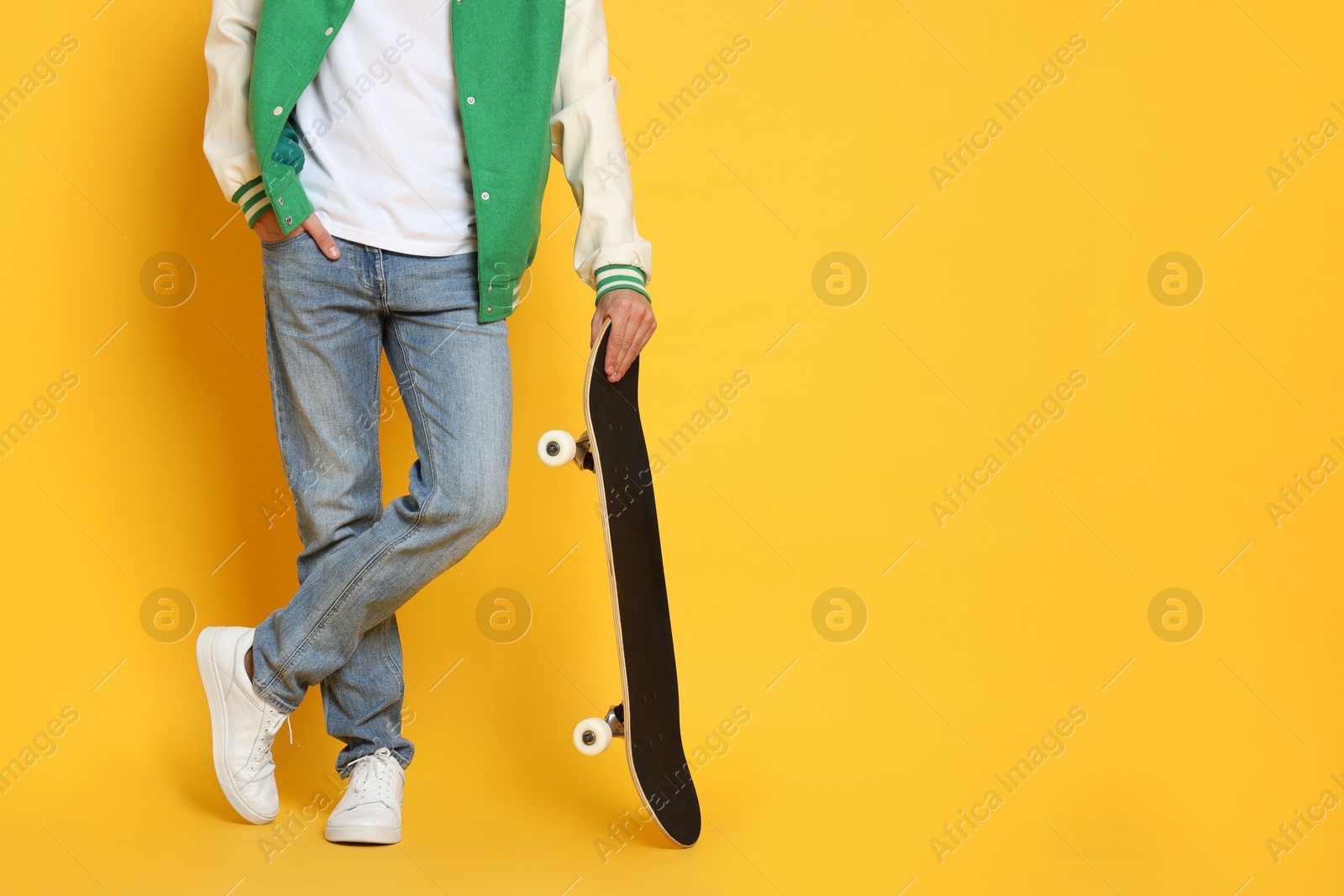 Photo of Man with skateboard on orange background, closeup. Space for text