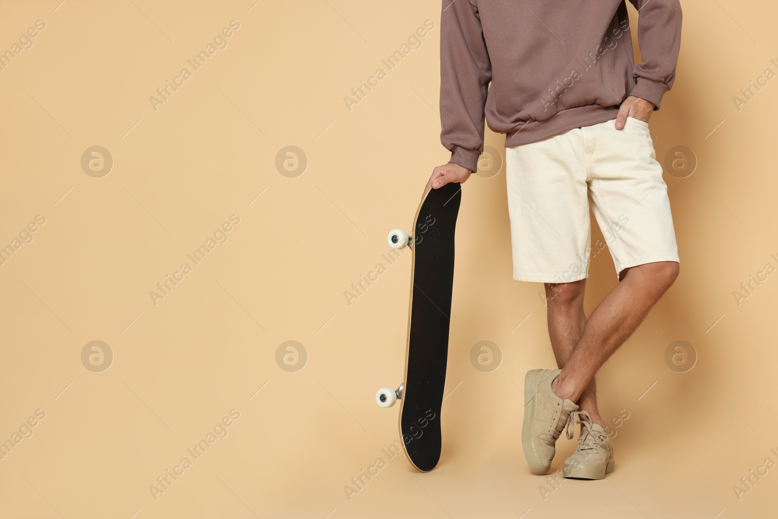 Photo of Man with skateboard on beige background, closeup. Space for text