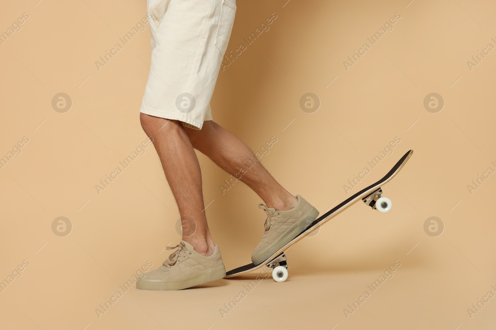 Photo of Man with skateboard on beige background, closeup