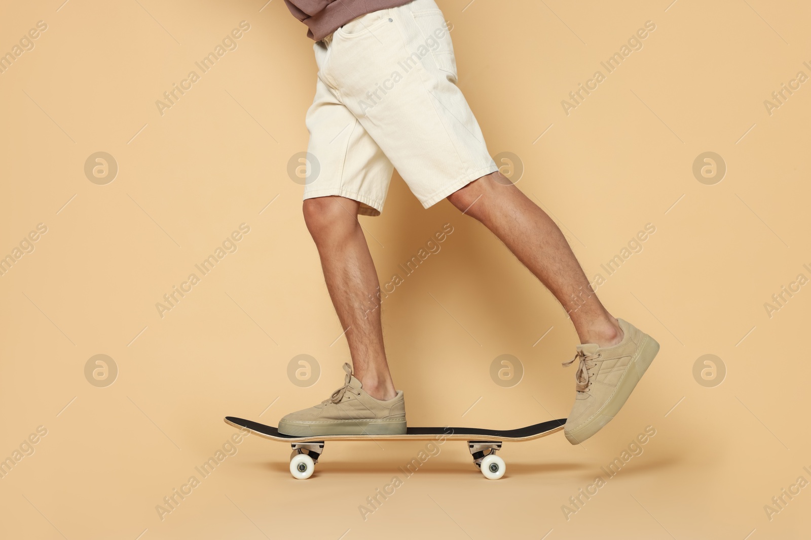 Photo of Man riding skateboard on beige background, closeup