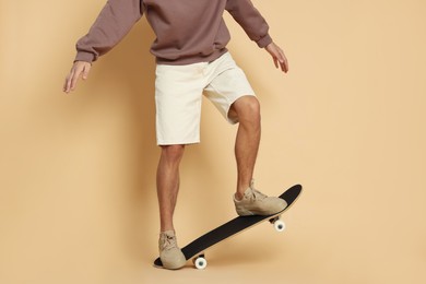 Photo of Man with skateboard on beige background, closeup