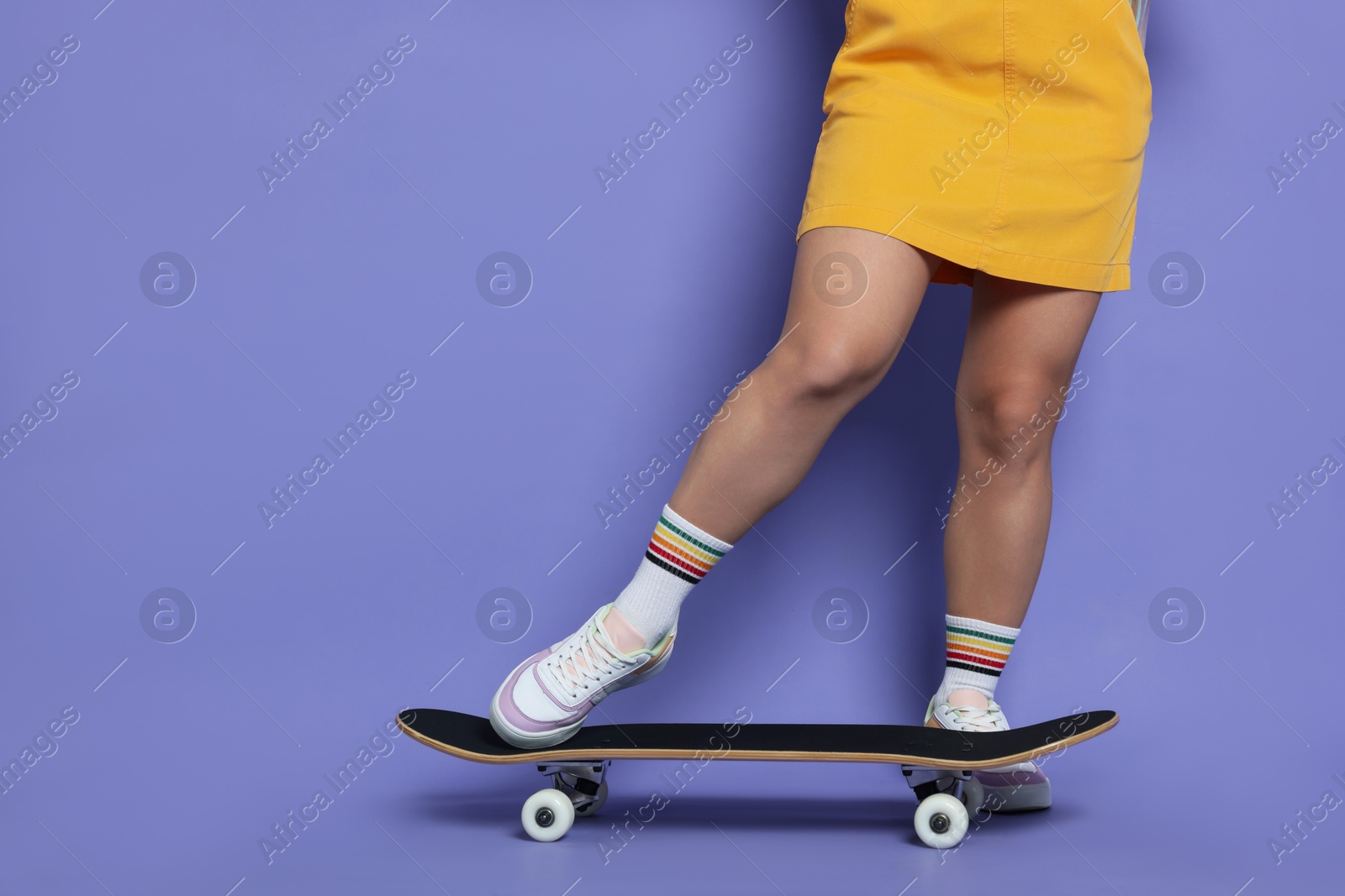 Photo of Woman with skateboard on violet background, closeup. Space for text