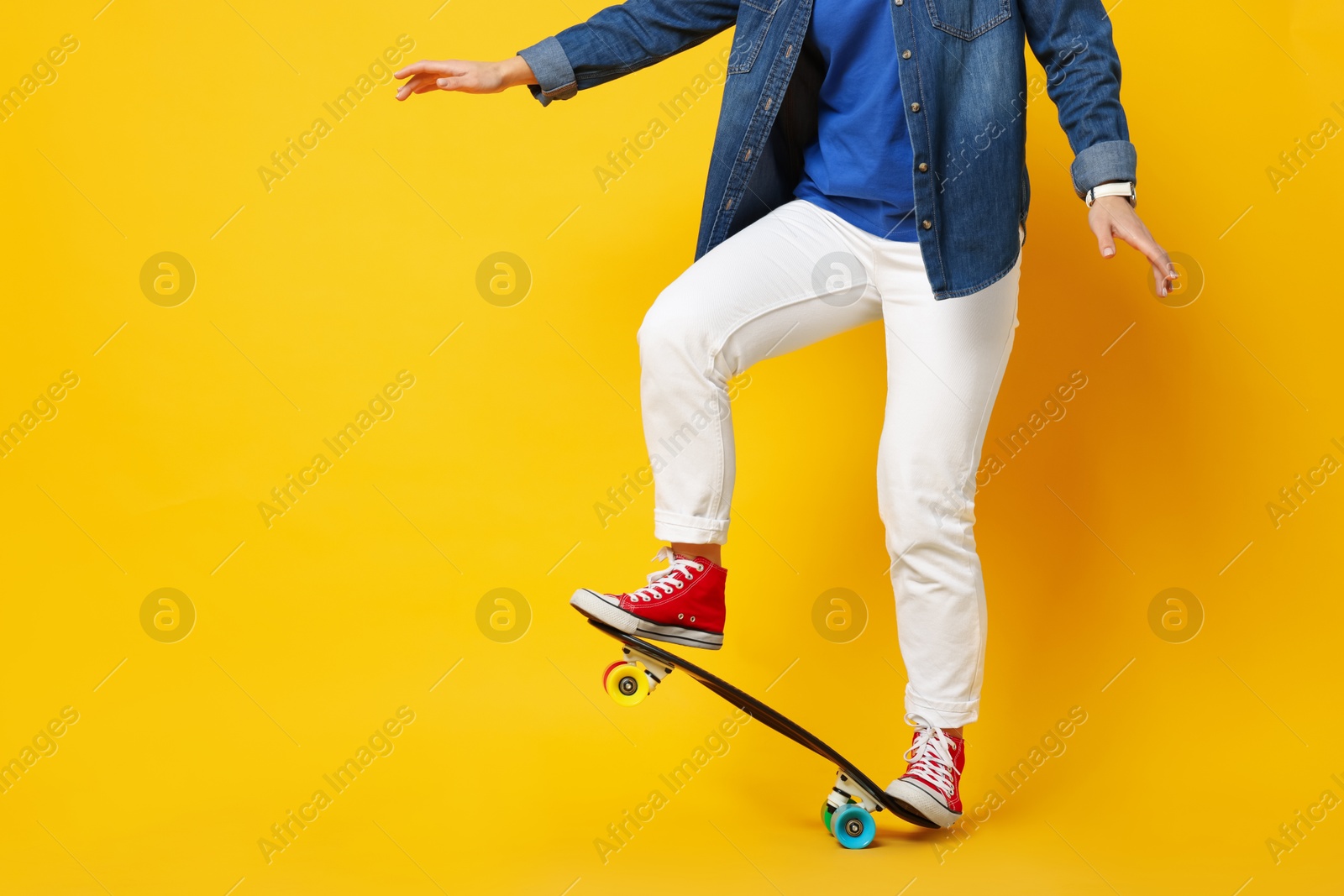 Photo of Woman with penny board on orange background, closeup. Space for text