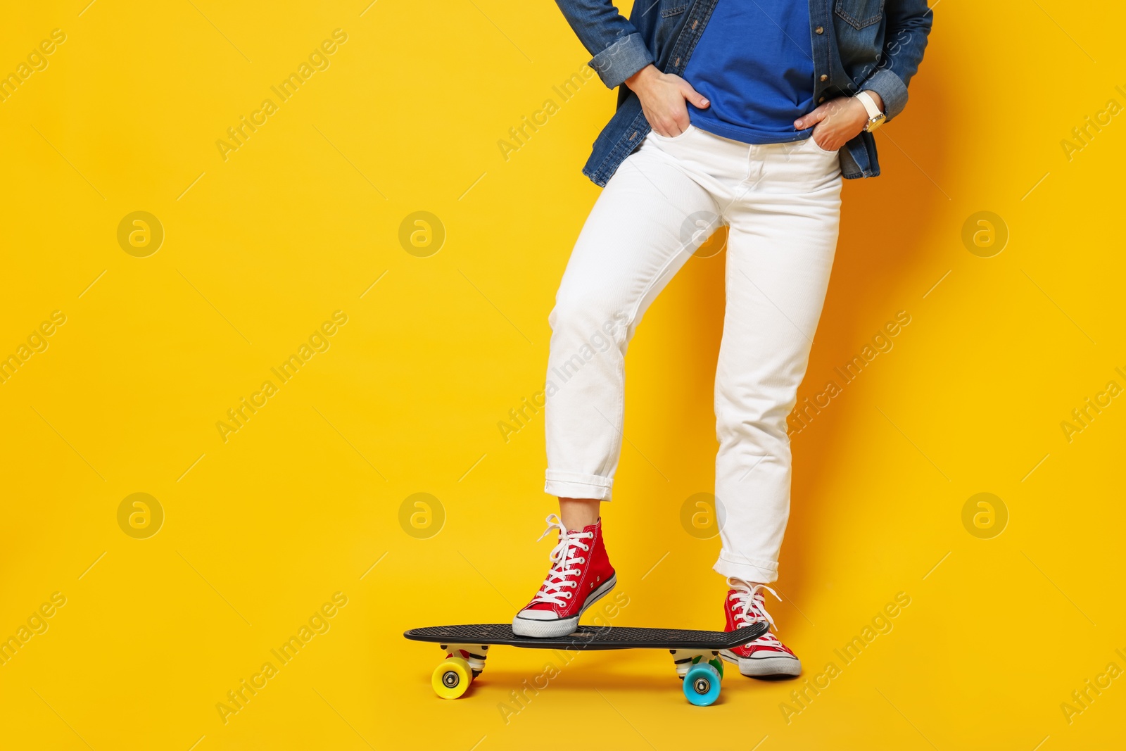 Photo of Woman with penny board on orange background, closeup. Space for text