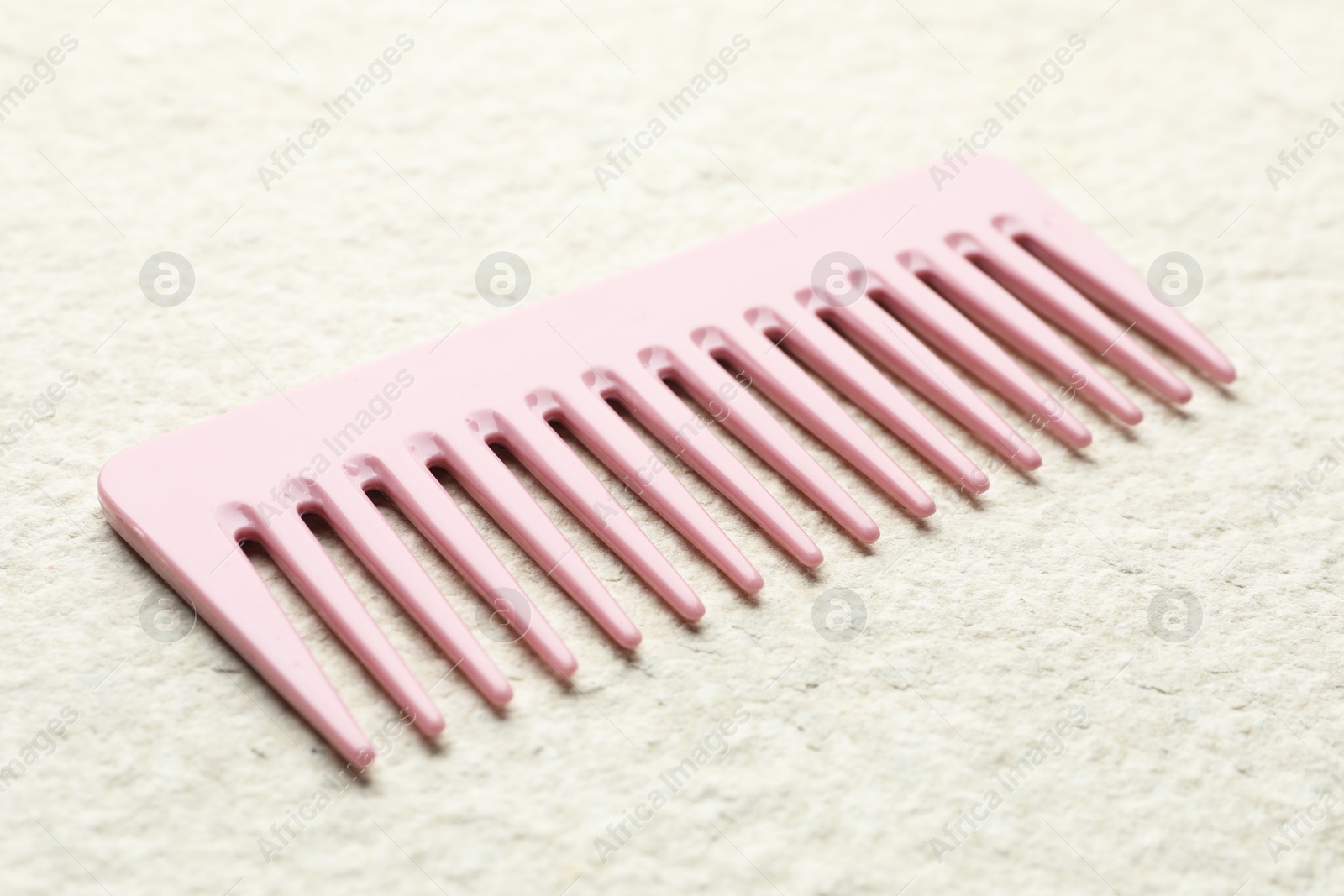 Photo of One pink plastic comb on beige background, closeup