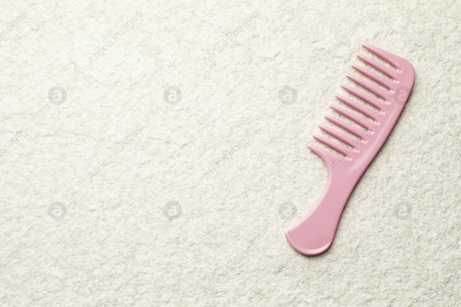 Photo of One pink plastic comb on beige background, top view. Space for text