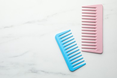 Photo of Different plastic hair combs on white marble table, top view. Space for text