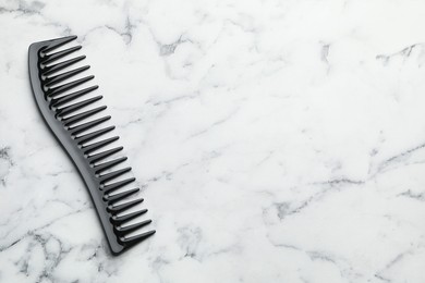 Photo of One black plastic comb on white marble table, top view. Space for text