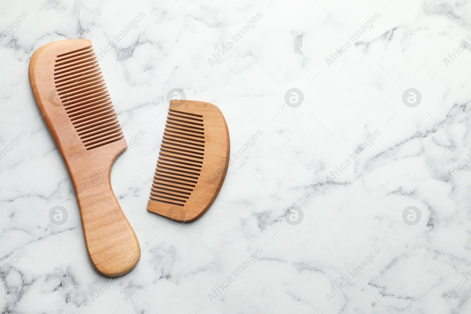 Photo of Different wooden hair combs on white marble table, top view. Space for text