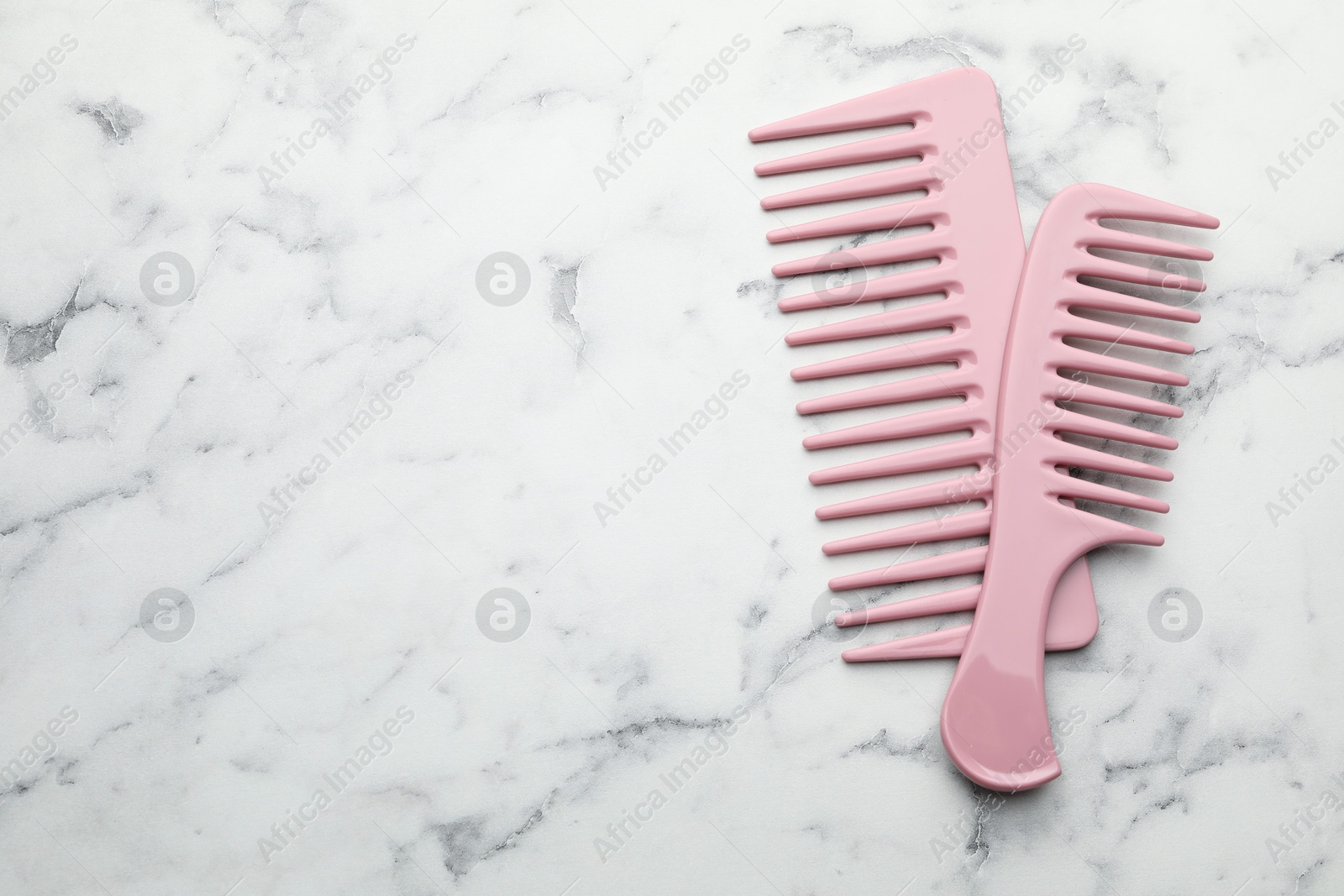 Photo of Different pink plastic combs on white marble table, top view. Space for text