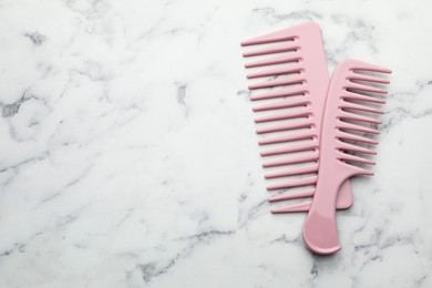 Photo of Different pink plastic combs on white marble table, top view. Space for text