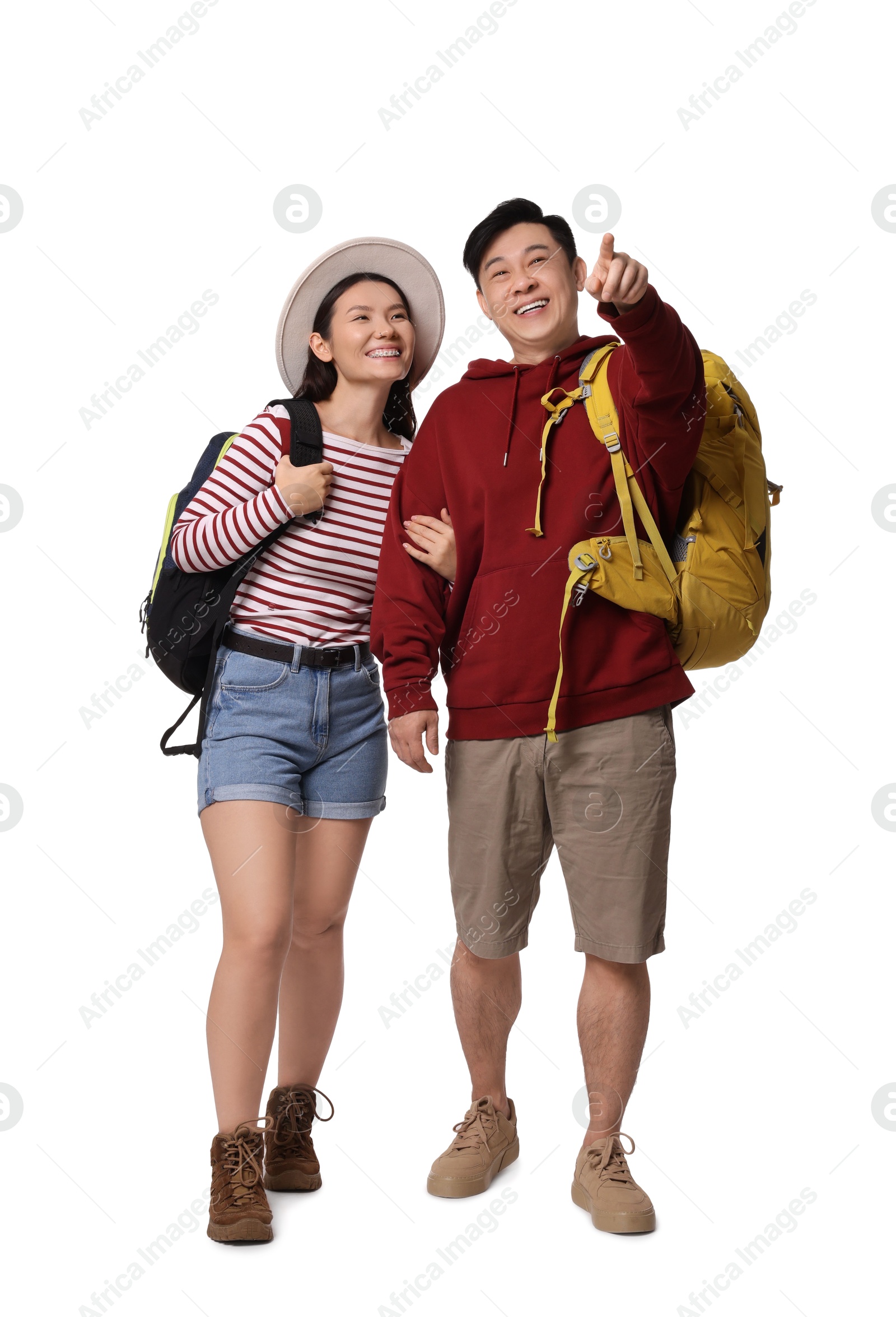 Photo of Happy travellers pointing at something on white background